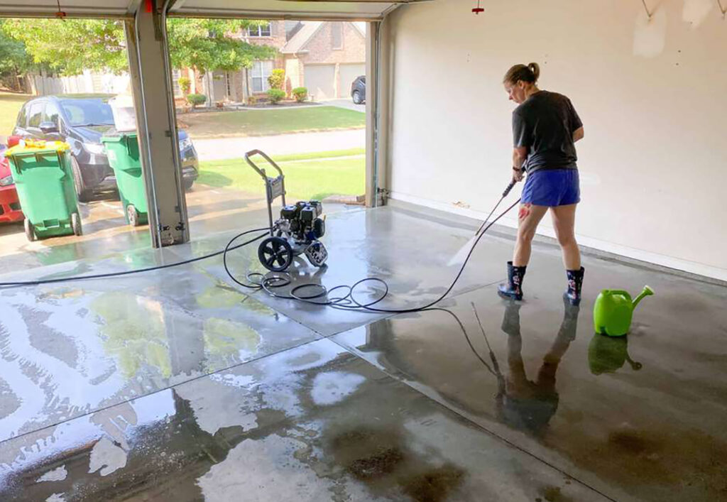 a woman cleaning a garage with a power washer
