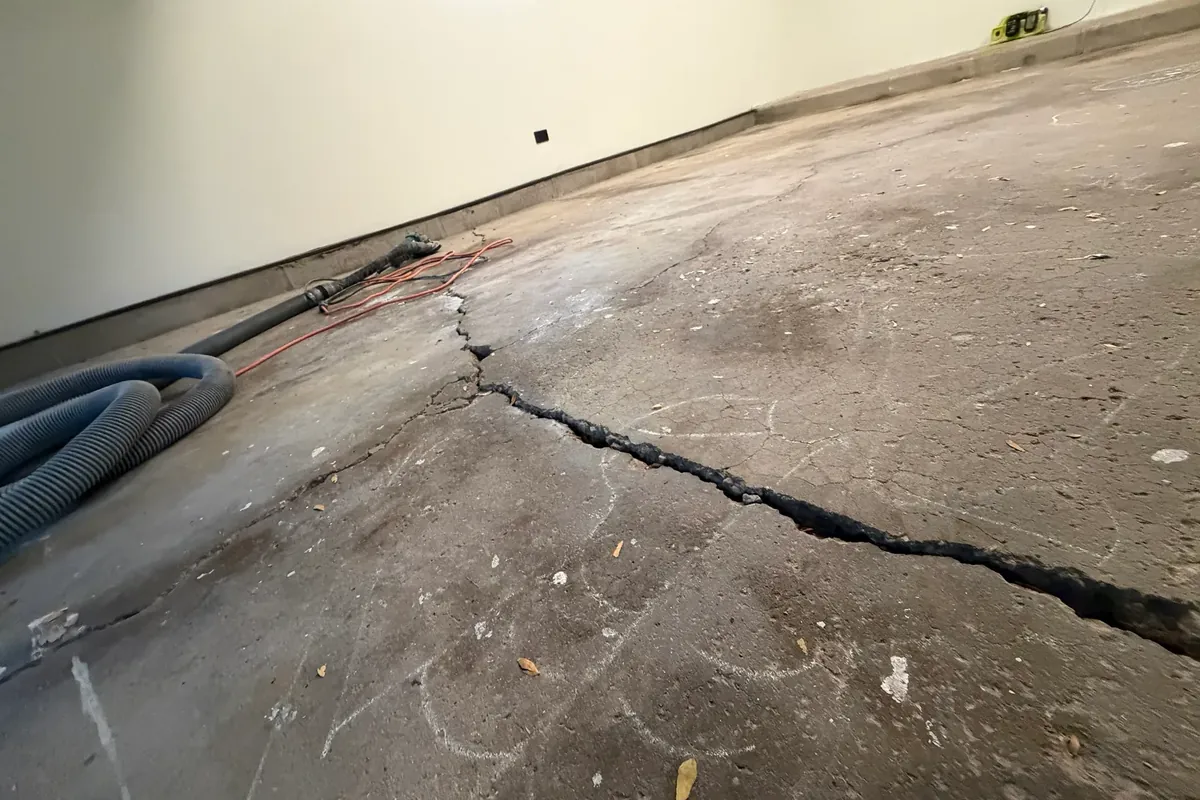 Crack running across a diamond-ground garage slab in Palatine, IL, with chalk marks, before it was cleaned out and filled