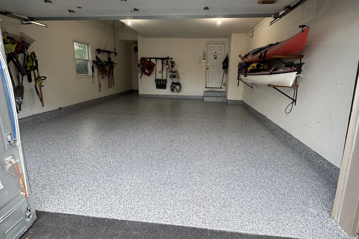 Finished 2-car garage floor coating in Antioch, IL with polyurea flake carried up the stem walls and onto the entry step for a continuous floor-to-wall seal