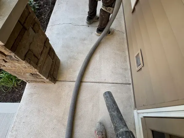 Front porch concrete being cleaned and prepped, with a visible crack across the slab