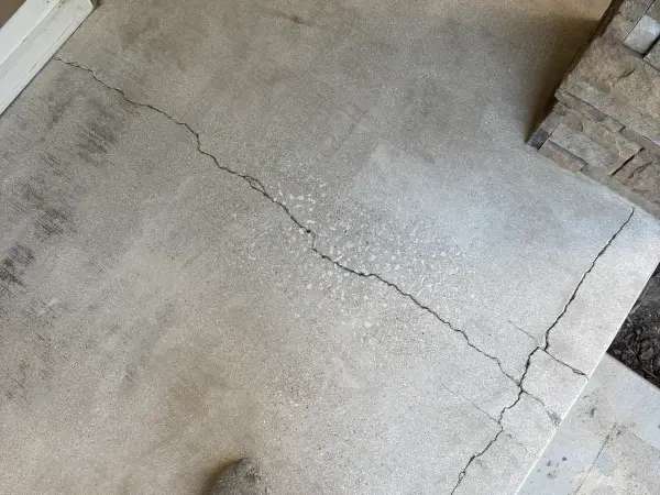 Bare porch concrete with long cracks and surface stains before coating