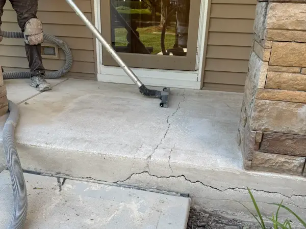 Vacuuming cracked porch step during prep before crack repair and coating