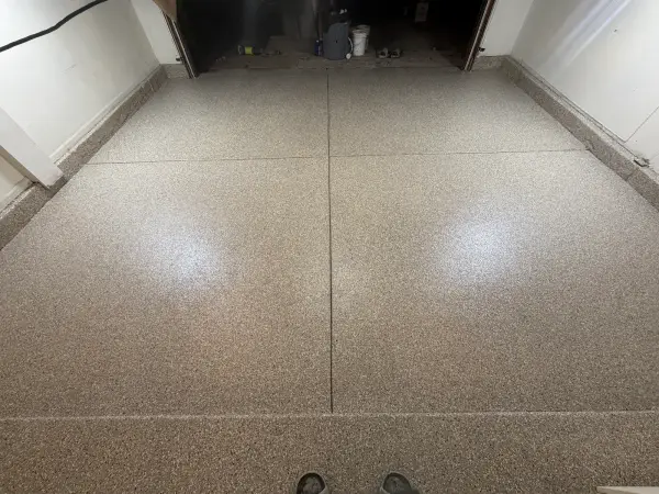 Finished polyurea garage floor in Creekbed flake blend with coated stem walls