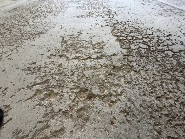 Close-up of spalled, flaking concrete surface on garage floor before repair