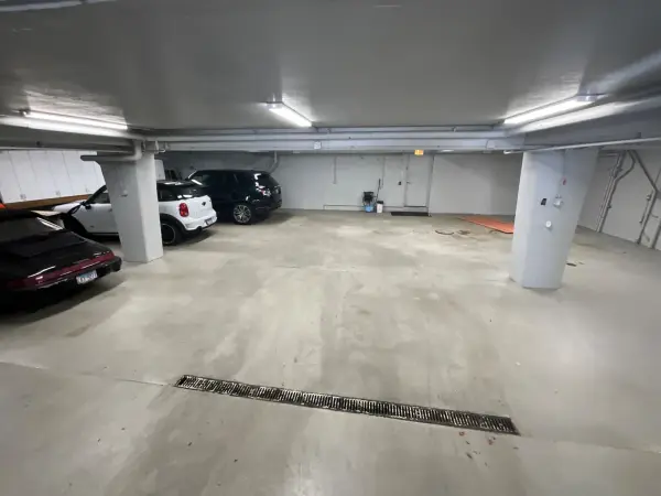 Before: bare concrete floor in an underground parking garage with trench drain