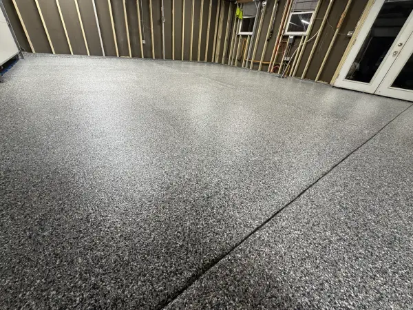Close view of gravel flake polyurea finish across garage floor joint