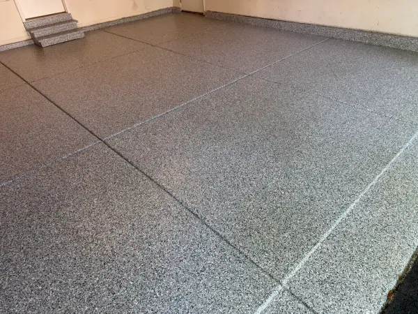 Gloss polyurea flake finish across garage slab with crisp control joint lines