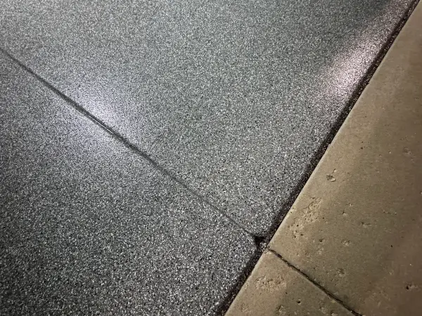 Close-up of gray flake coating with clean edge at the apron