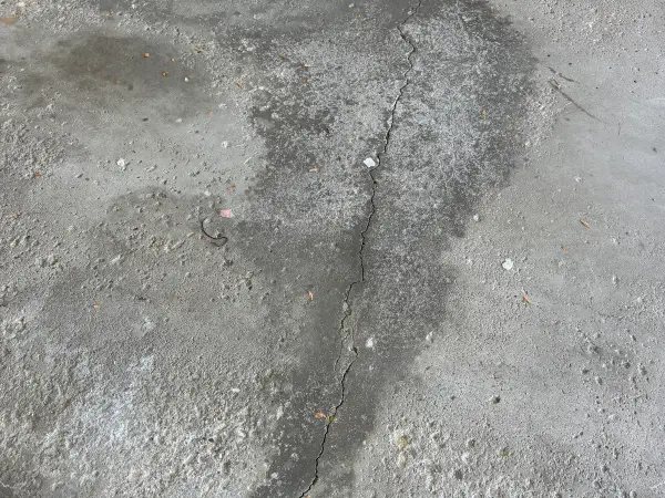 Before: cracked garage floor with dark stains and worn bare concrete