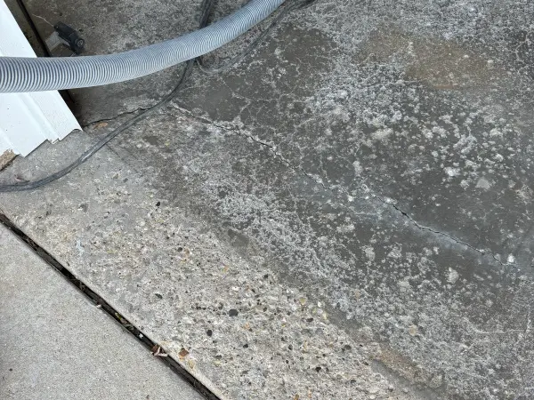 Garage floor edge with cracks and pitted concrete during prep work