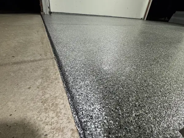 Finished gray flake polyurea coating with glossy topcoat at garage entry