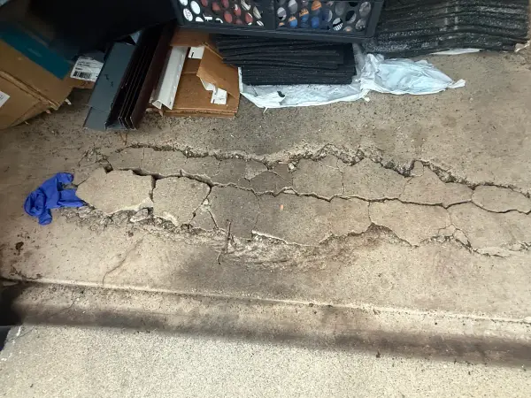 Badly cracked and broken concrete across the garage floor before repair