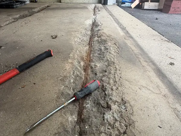 Long garage floor crack chiseled open and cleaned out for repair