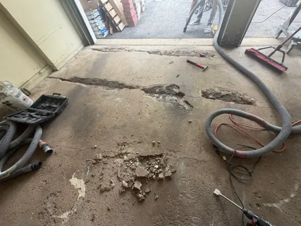 Damaged concrete chipped out along cracks near the garage door opening
