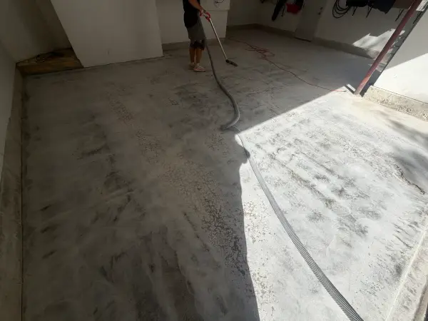 Vacuuming dust from freshly ground garage floor during surface prep