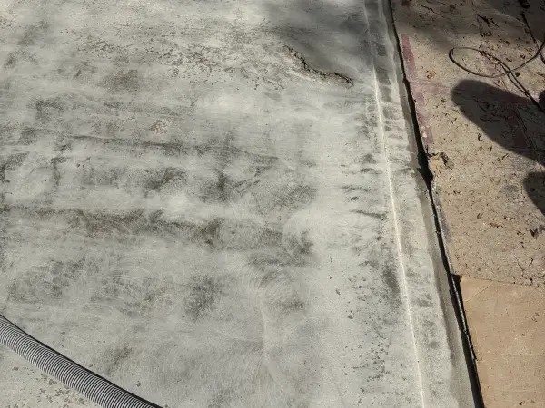 Ground garage floor edge near the door with visible crack and spalling