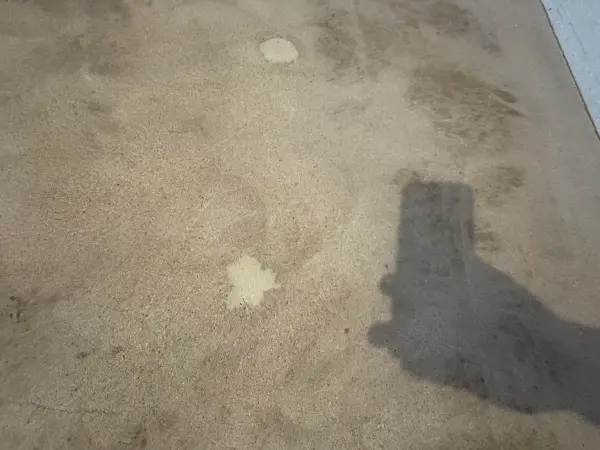 Concrete garage floor with dark stains and patched spots before coating